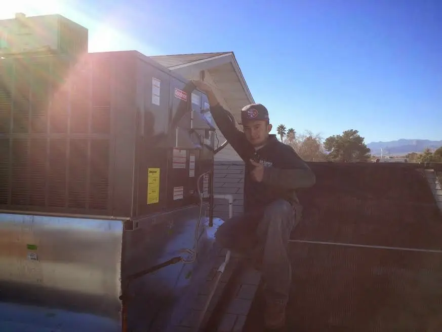 HVAC technician performing AC Tune-Up on a rooftop unit in West Lealman